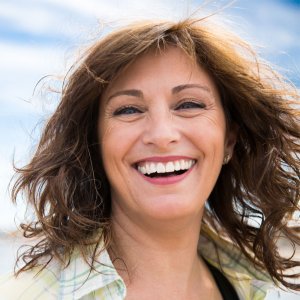 Elevation Med Spa Lone Tree Colorado smiling middle aged woman with hair blowing in the wind at the beach